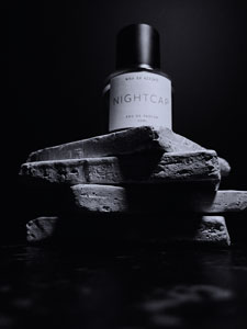 Black and white image of Who is Elijah Nightcap perfume sitting on a tower of sandstone blocks with light shining on it from the top right creating contrasting shadows